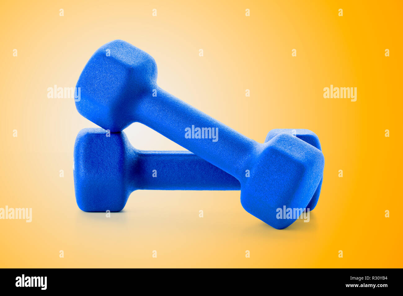 Two small blue dumbbells on bright orange background, close-up and front-view Stock Photo