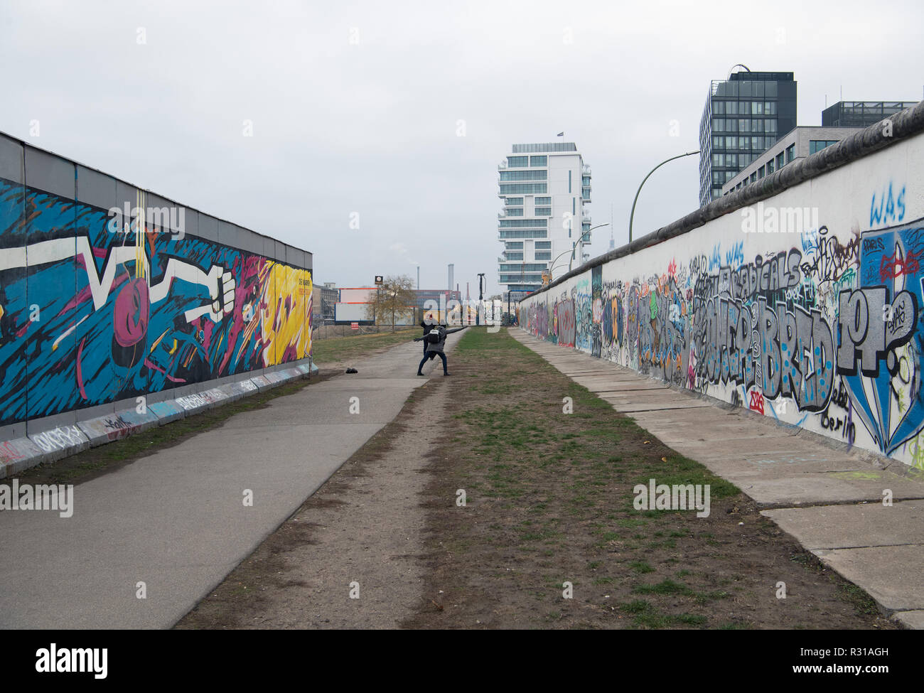 Berlin, Germany. 21st Nov, 2018. Tourists photograph themselves after a press conference of the Berlin Wall Foundation on new offers for the East Side Gallery next to a piece of wall (l) that recently had to be moved after the opening of a wall. In the background is the completed new construction of a high-rise residential building. Credit: Soeren Stache/dpa/Alamy Live News Stock Photo