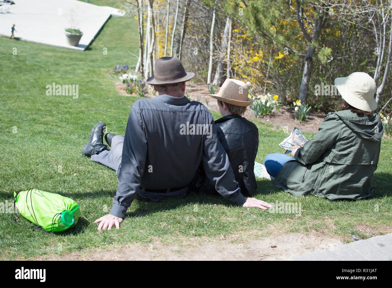 A Small Family In Hats Stretched Out In The Grass Stock Photo Alamy