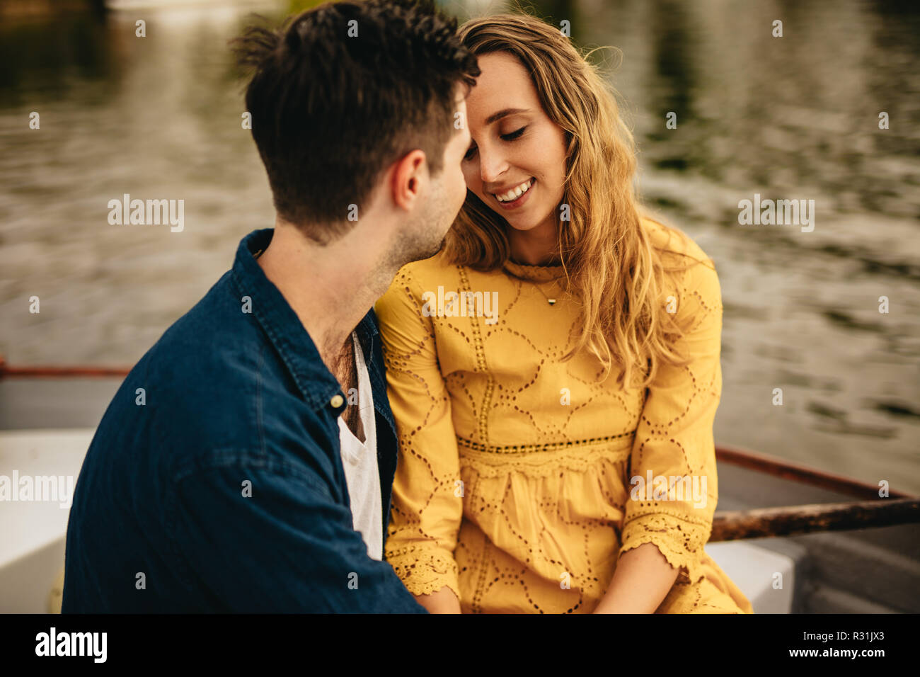 Romantic couple sitting in a boat together and talking. Young man and woman in love sitting together in a boat on a date. Stock Photo