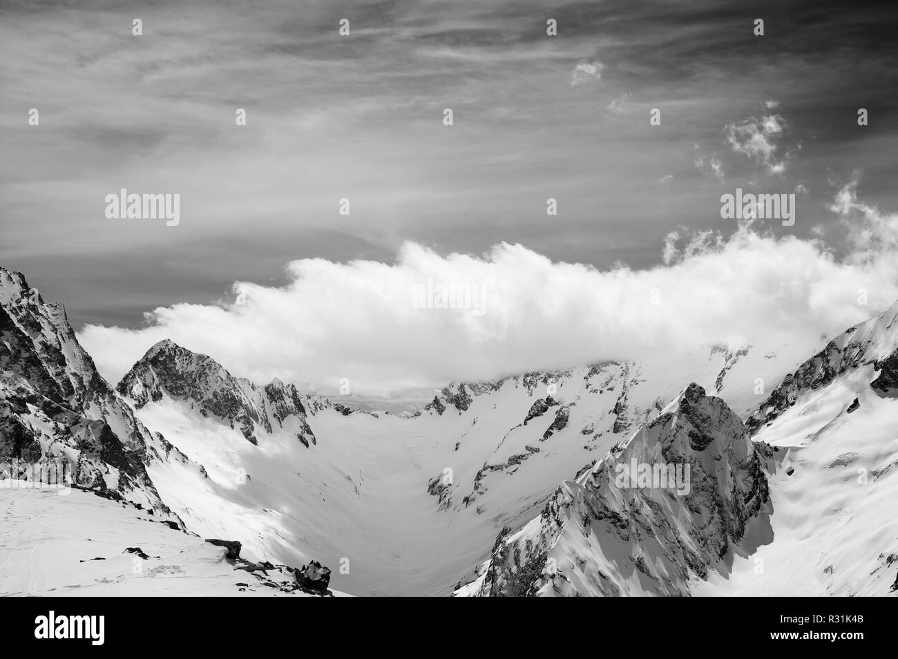 Black and white view on snowy sunlight mountains in clouds. Caucasus ...
