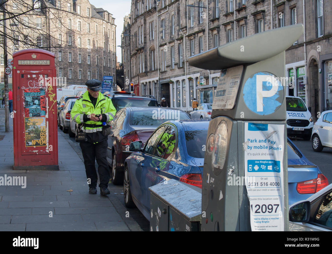 Parking attendant wearing uniform and checking cars in a street of ...