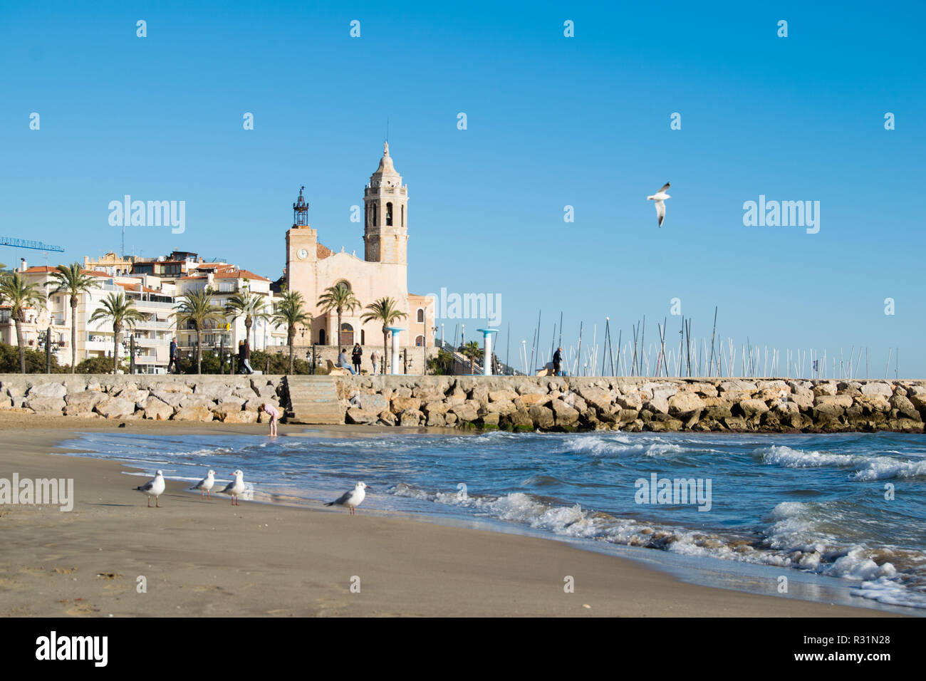 The beautiful town of Sitges with seagulls, winter Spain, Landscape of the coastline in Sitges, Parròquia de Sant Bartomeu i Santa Tecla Stock Photo
