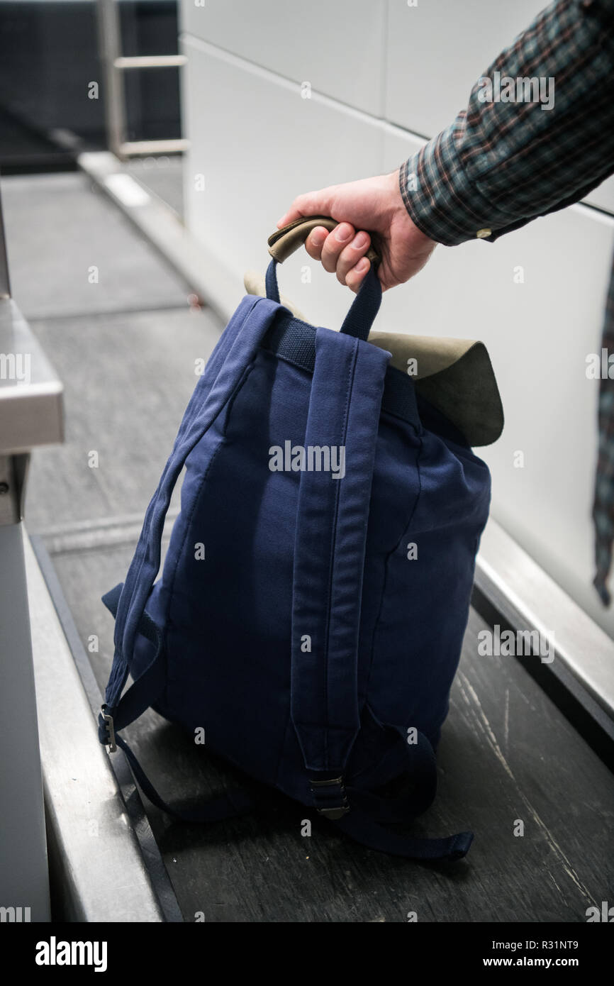 Man's hand with a backpack on luggage conveyor belt system at check in