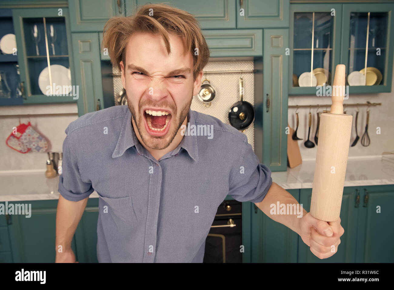 Man with angry face shout with rolling pin in kitchen. Cook, bake, home