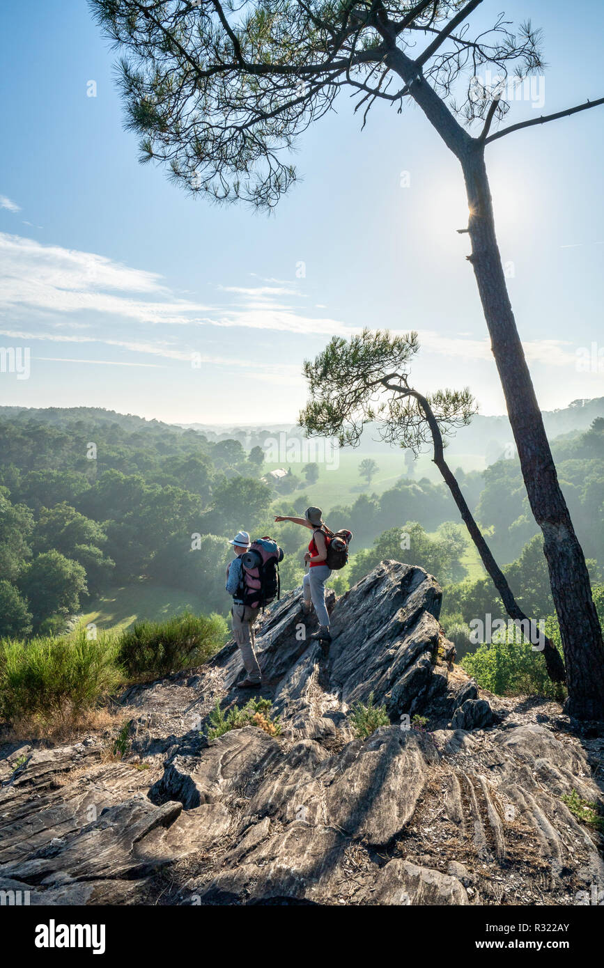 Hiker couple walk on a mountain trail, overlooking the valley. Stock Photo