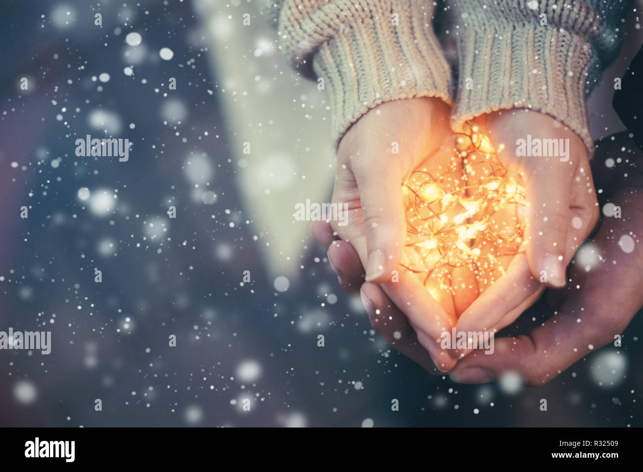 Close view of a couple holding warm Christmas lights Stock Photo