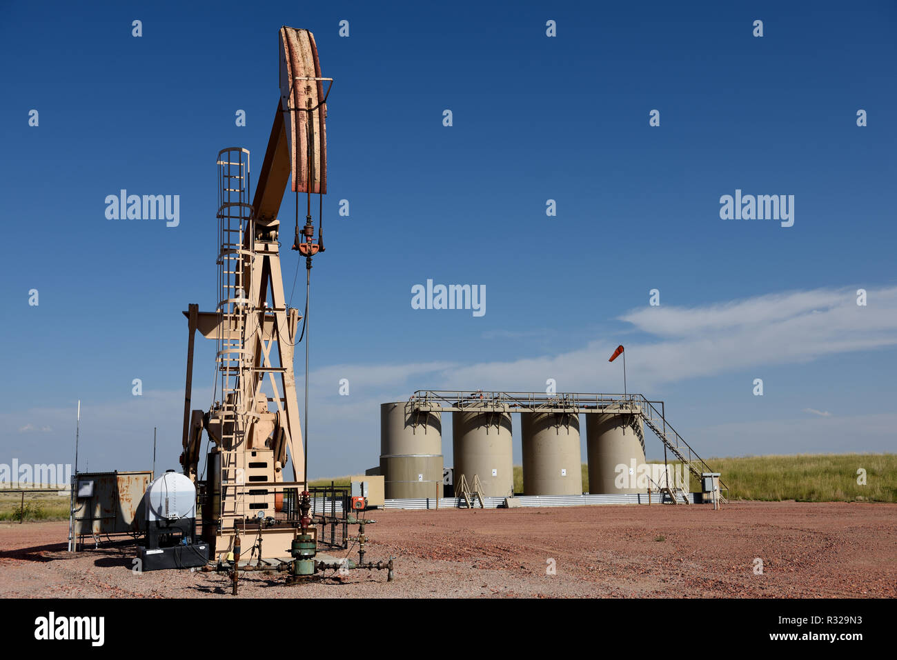 Crude oil well site, pump jack, production storage tanks, blue sky