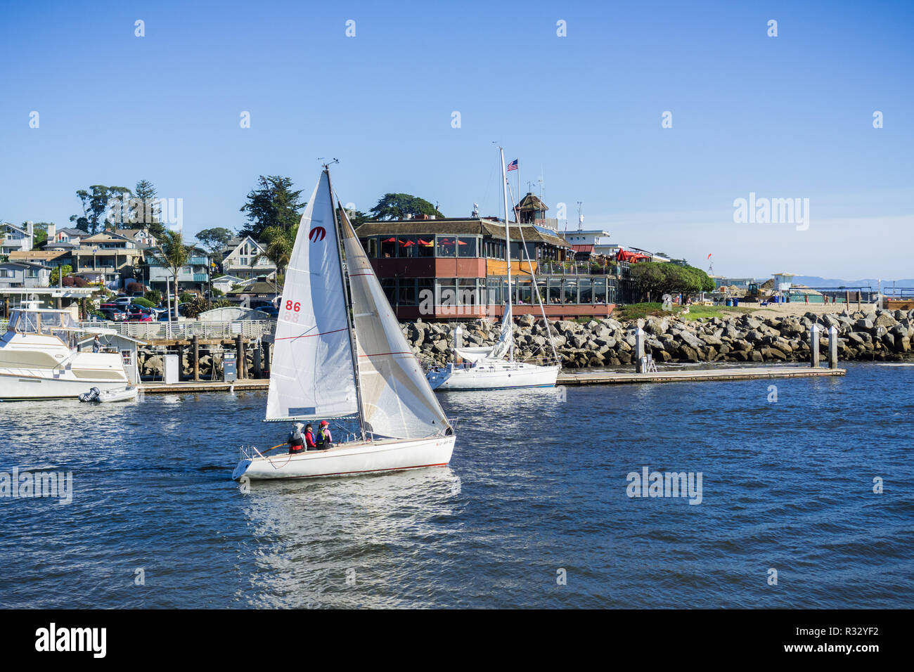 November 12, 2017 Santa Cruz/CA/USA - Sailing ship leaving Santa Cruz harbor; restaurants and houses in the background Stock Photo