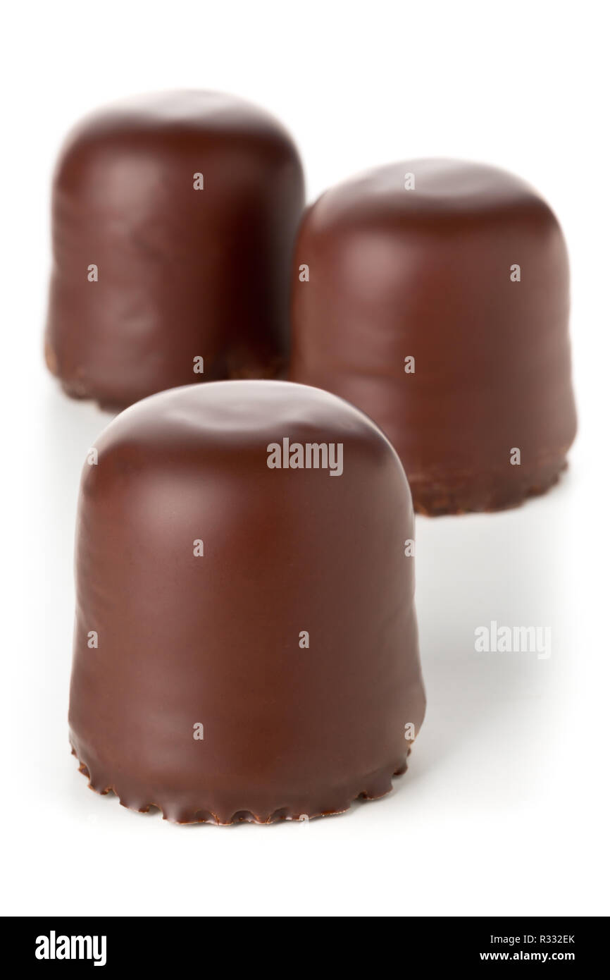 Three whole german specialty sweets 'Schokokuss' or 'Schokoschaumkuss' (small chocolate-covered cake filled with foamy sugar) over white background Stock Photo