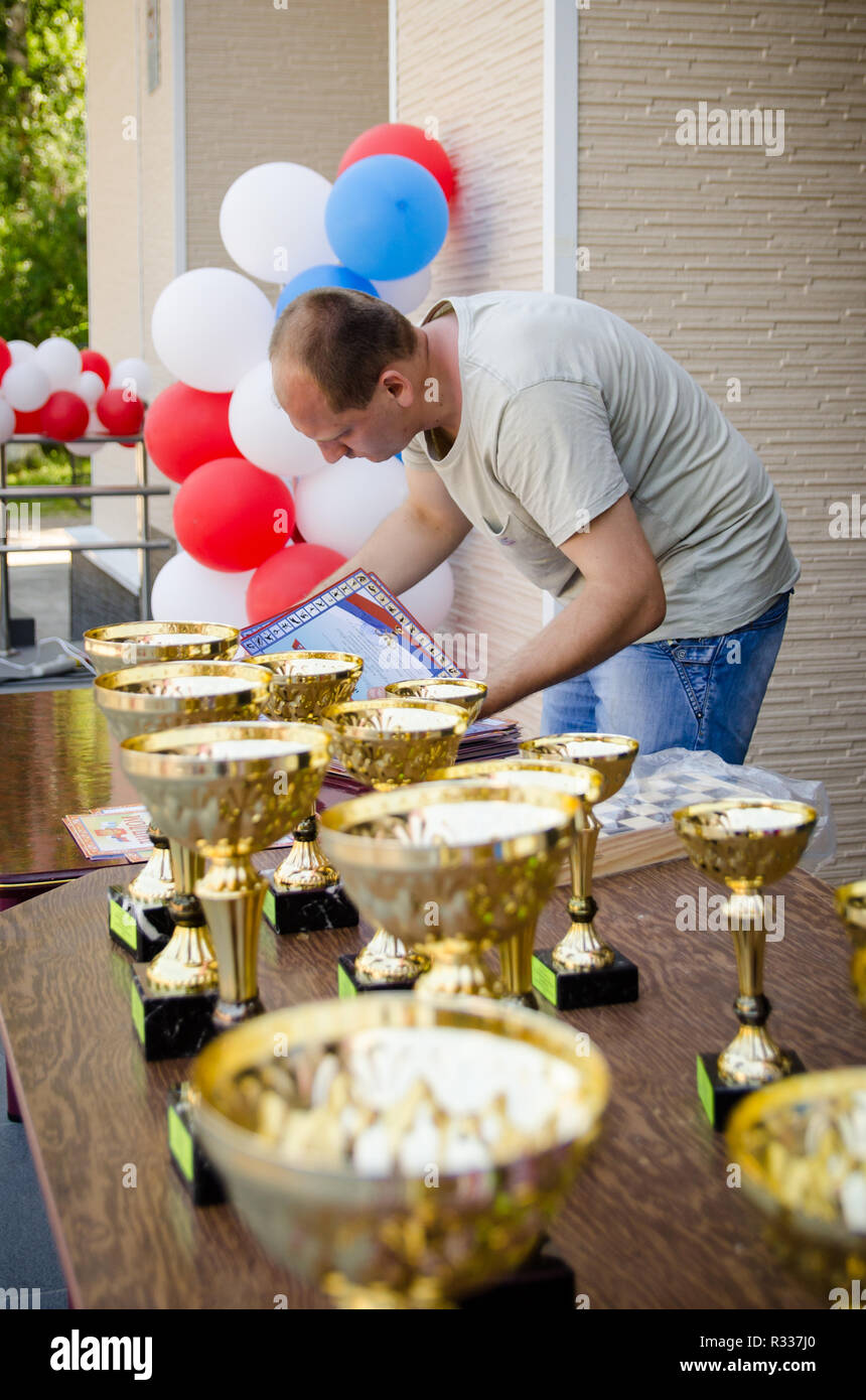 Komsomolsk-on-Amur, Russia - August 1, 2016. Public open Railroader's day. referee prepares certificates and sports cups for awarding athletes. vertic Stock Photo