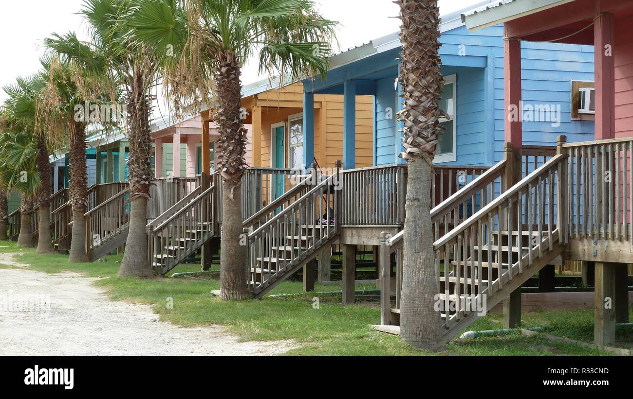 Row Of Small Colorful Wooden Beach Houses And Palm Trees On The