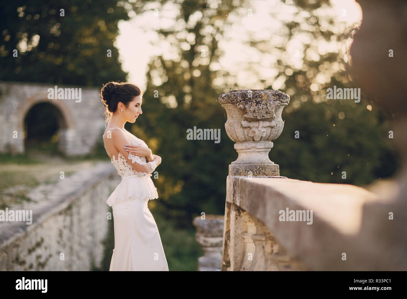 bride in a white dress standing near a stone fence Stock Photo - Alamy