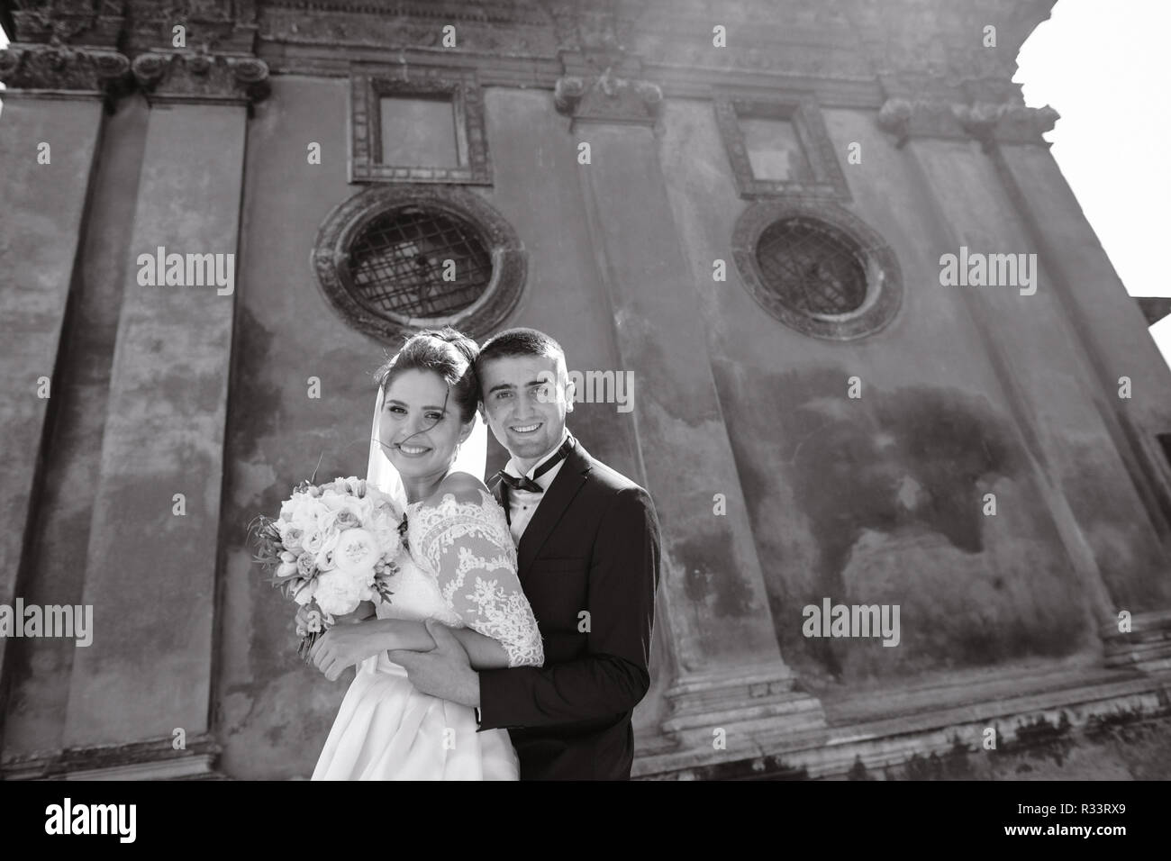 bride and groom standing near the old brown house Stock Photo - Alamy