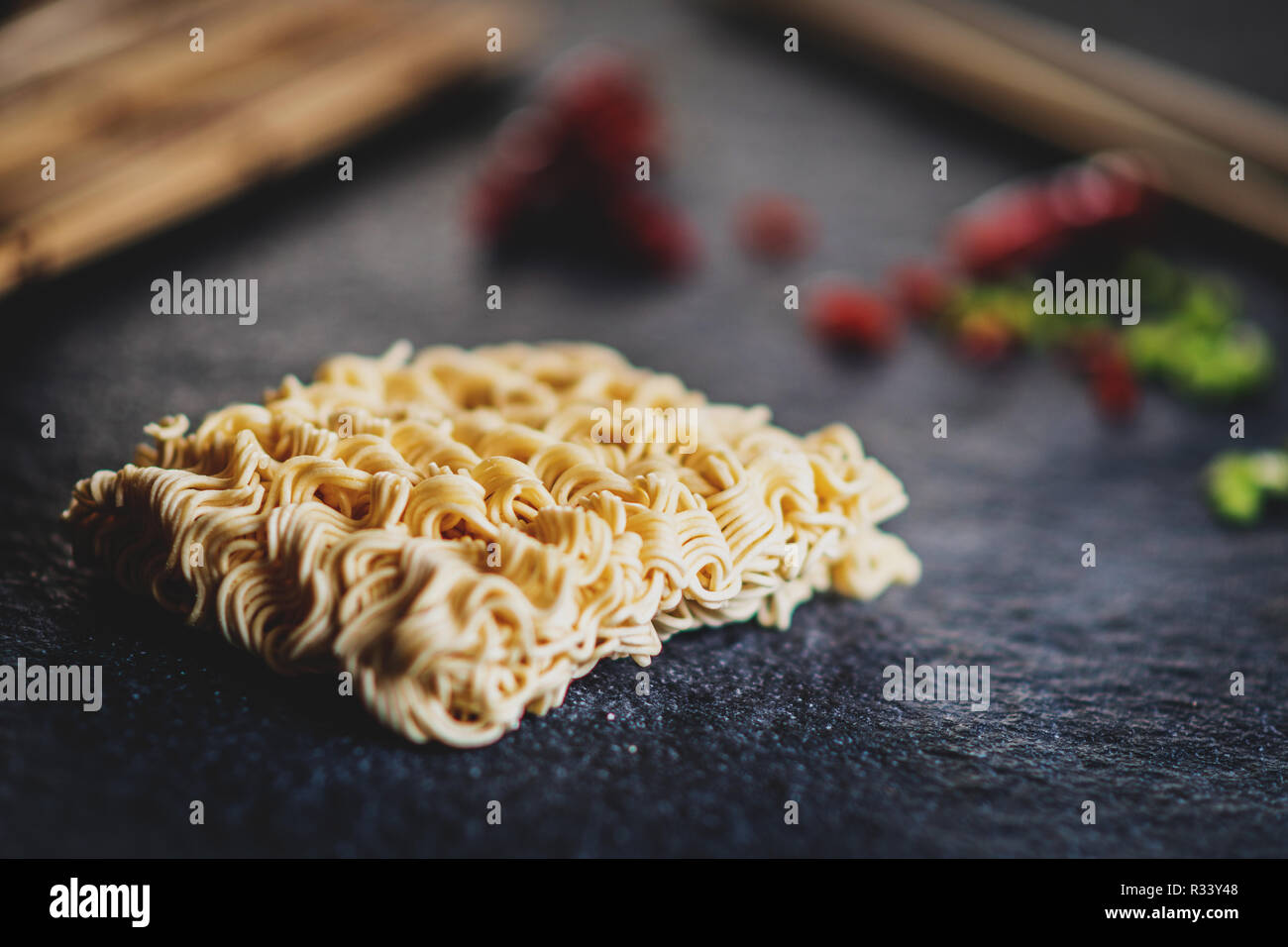 Asian instant noodles with and red chili peppers and green onion and chopsticks on black stone table Stock Photo