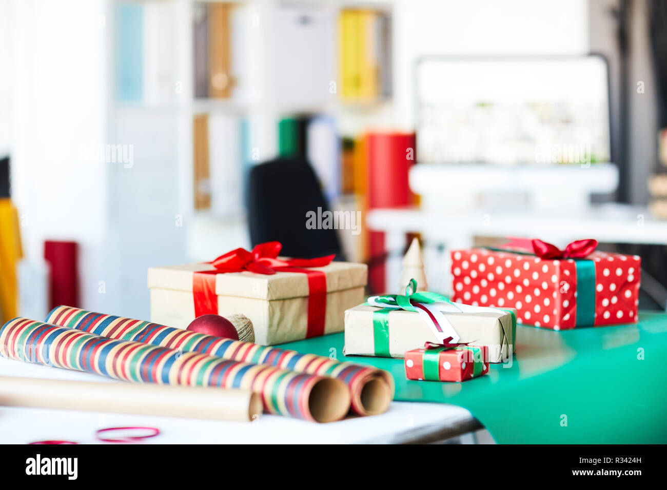 Group of packed gifts in boxes and rolled wrapping paper on table in studio Stock Photo