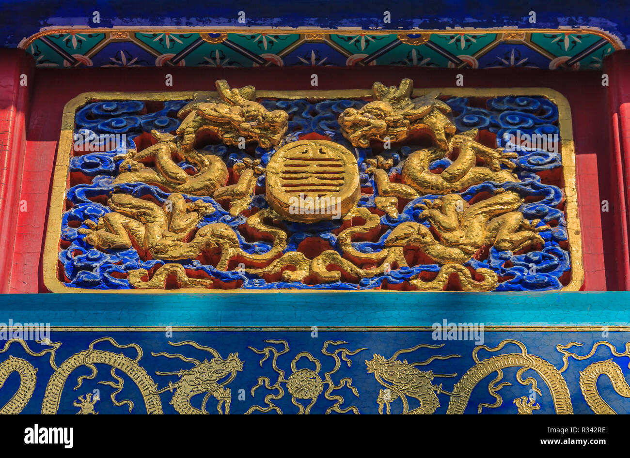Ornate carved and painted beam and rafters with traditional Chinese golden dragon designs in Buddhist Yong'An (Temple of Everlasting Peace) in Beihai  Stock Photo