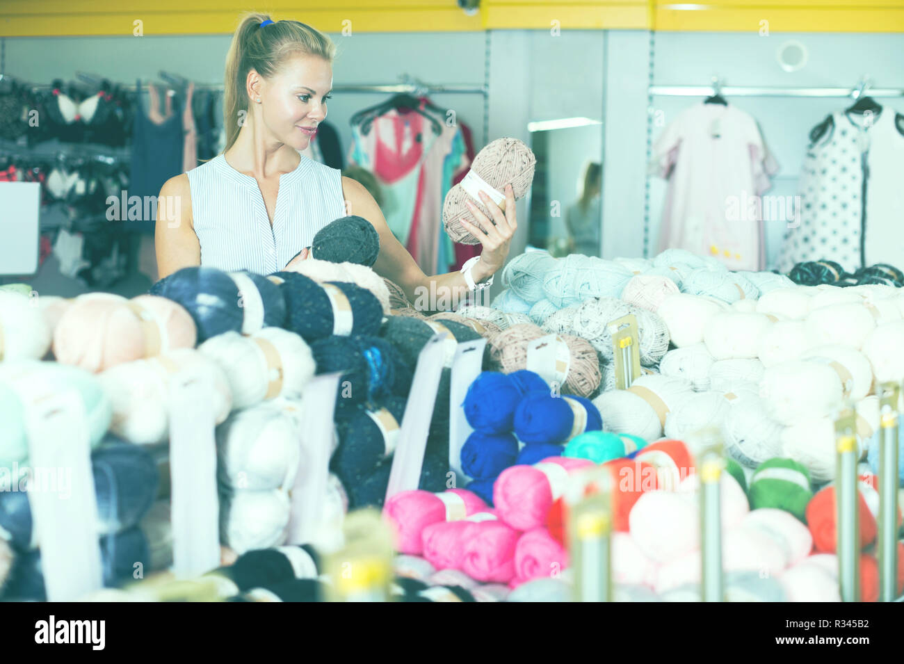 Portrait of adult positive woman holding colored thread for knitting ...