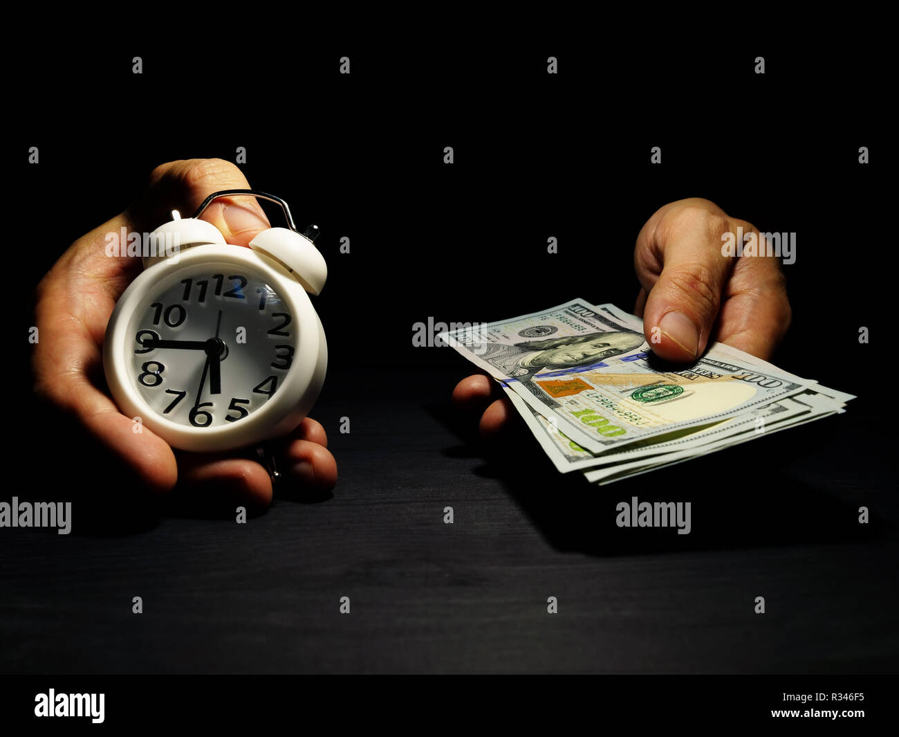 Time is money. Hands are holding alarm clock and dollar banknotes. Stock Photo