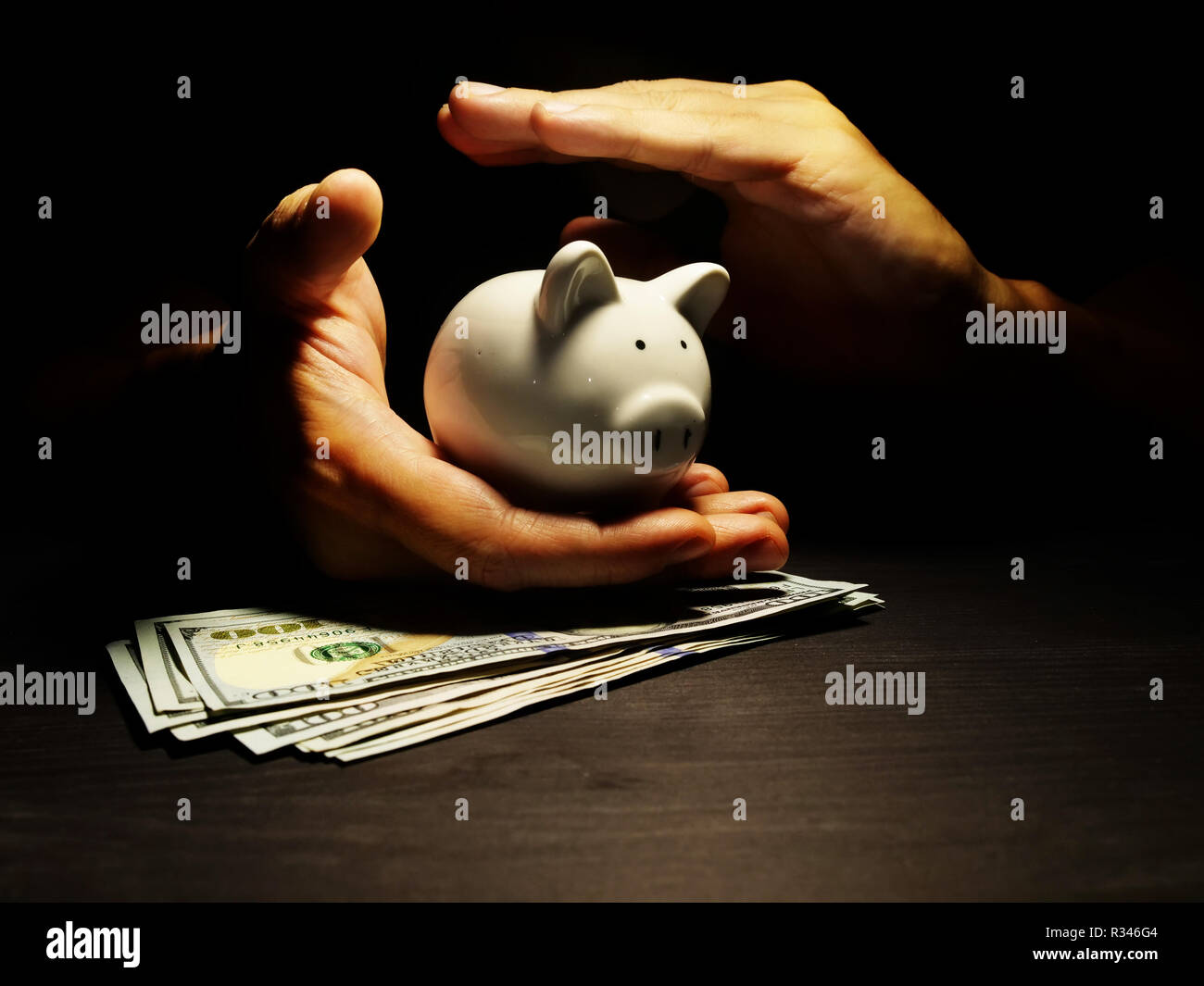 Savings protection. Hands protect piggy bank with dollars. Savings protection. Stock Photo