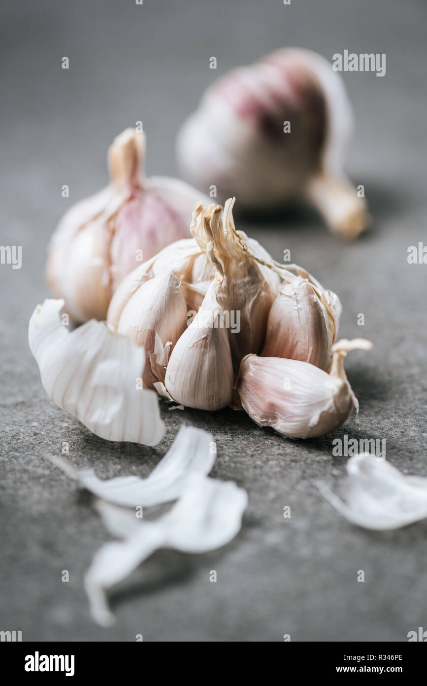 Close up view of ripe garlic bulbs and husk on grey surface Stock Photo