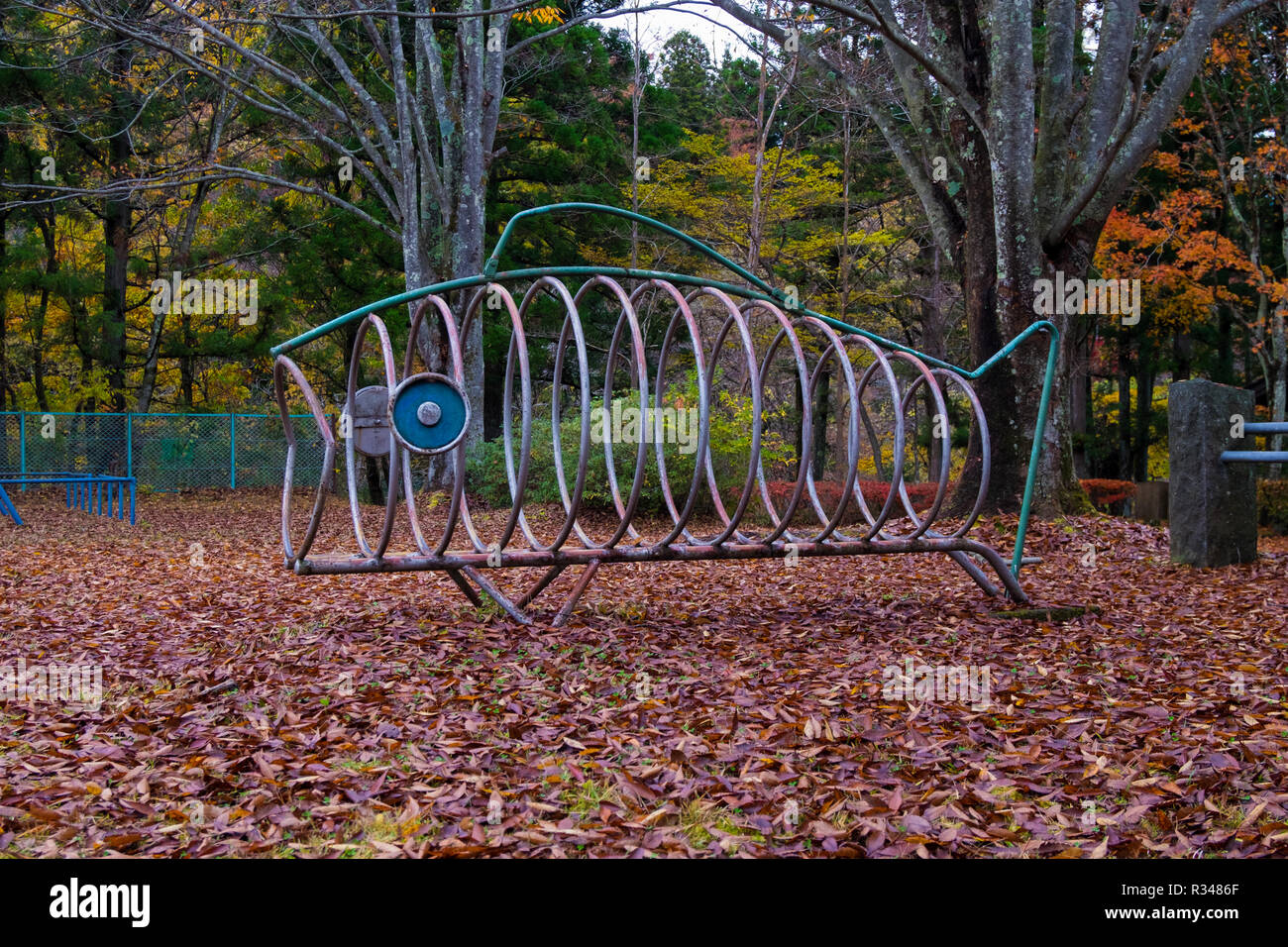 A piece of playground equipment shaped like a metal fish in a park in