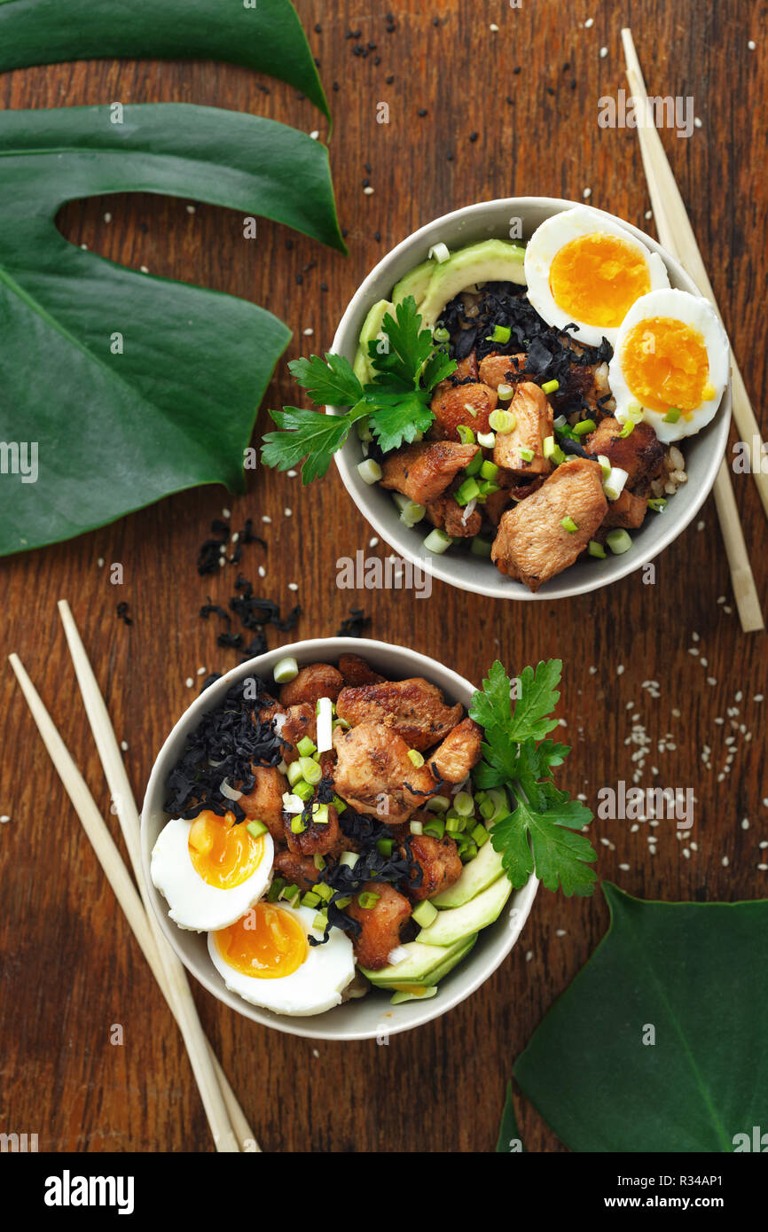 Asian food concept. Poke bowl of fried rice, chicken fillet and eggs top view Stock Photo