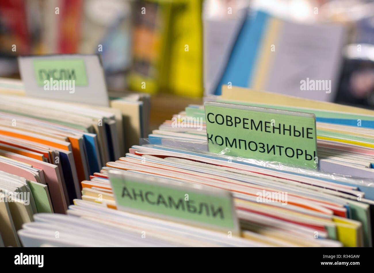 Edges of multi-colored musical notebooks put in a row with inscriptions in Russian 'modern composers' and 'ensembles' on a blurred background. Stock Photo
