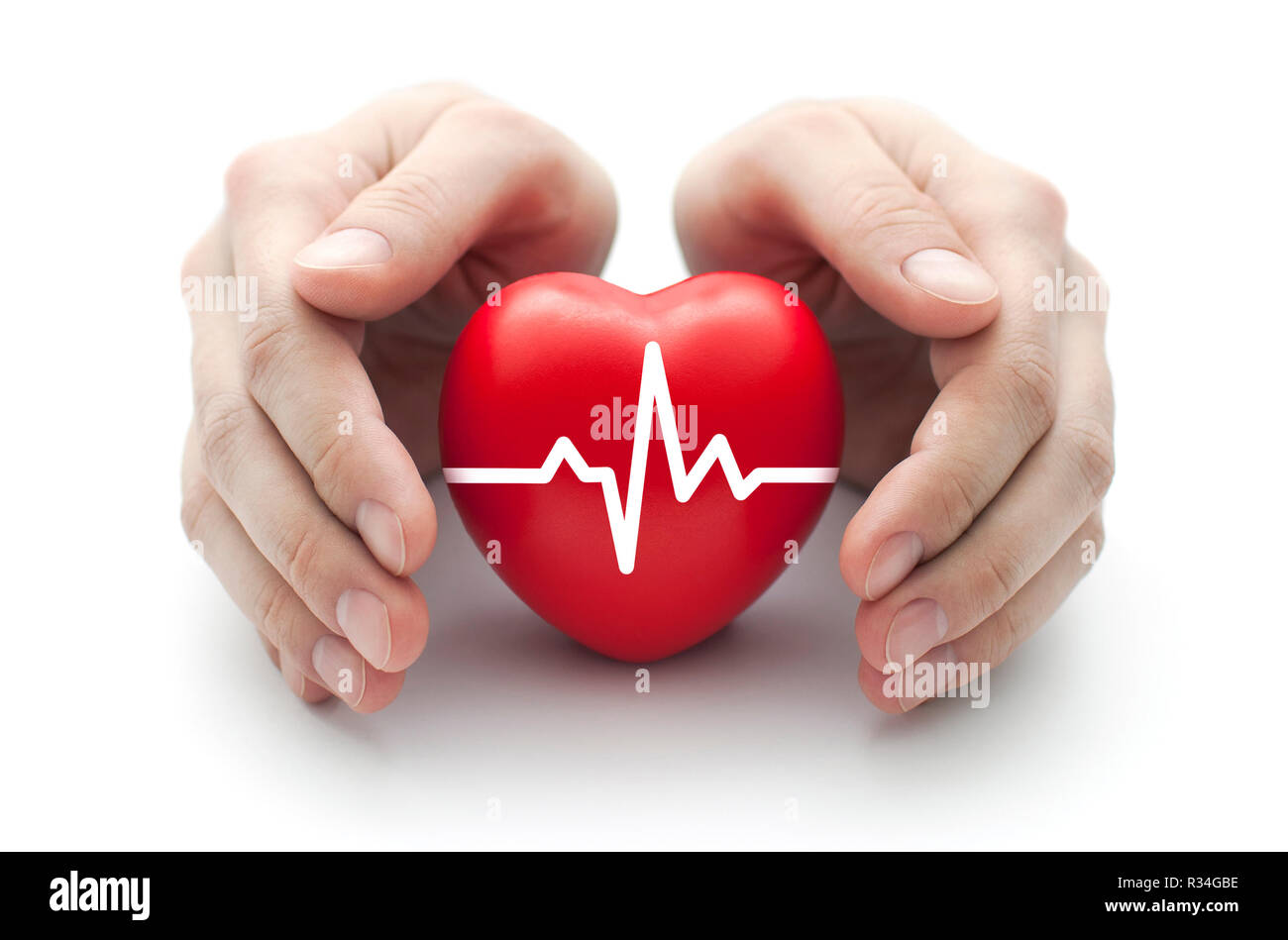 Red heart with pulse covered by man's hands. Stock Photo