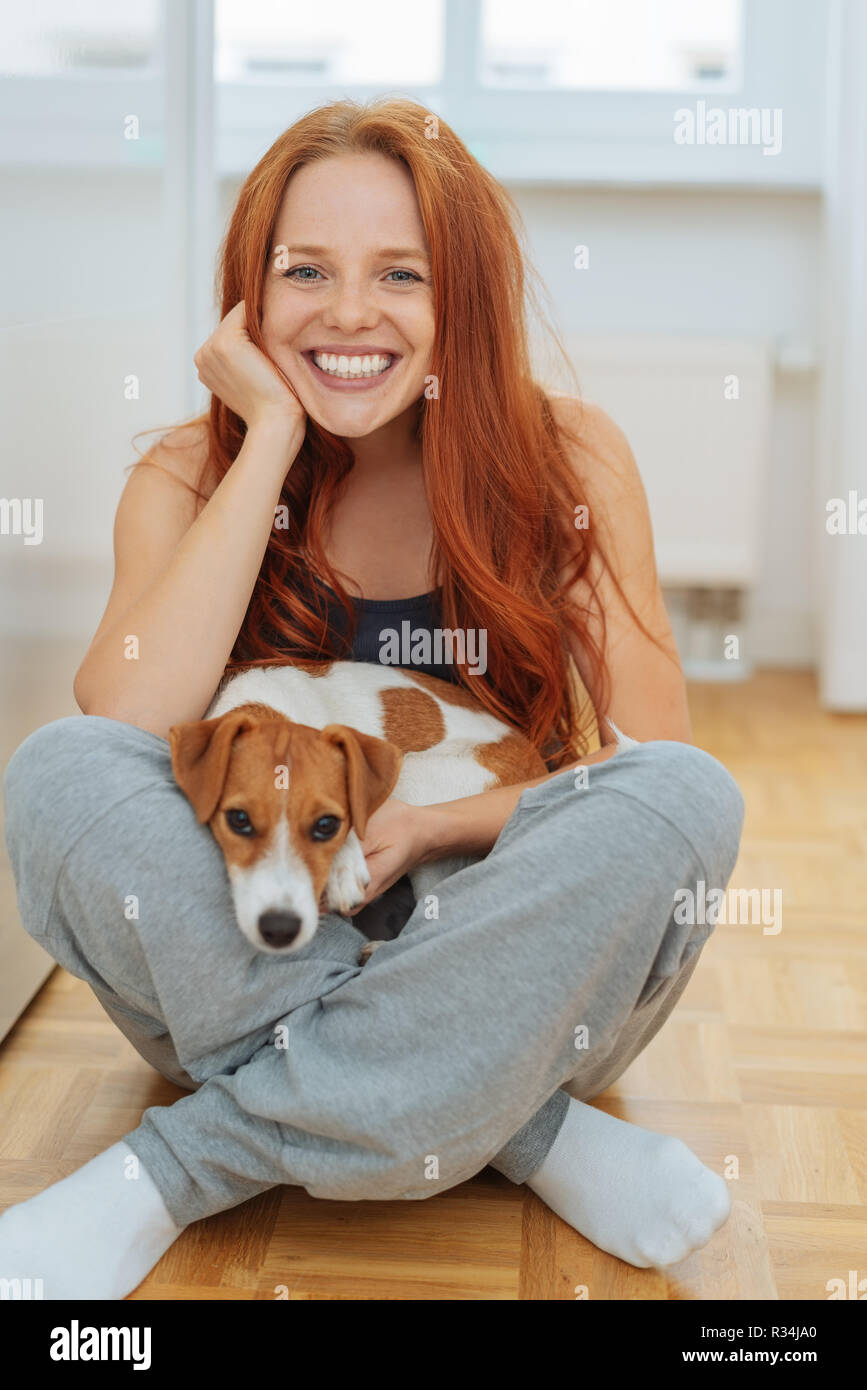 Friendly young woman relaxing with her terrier type dog sitting cross