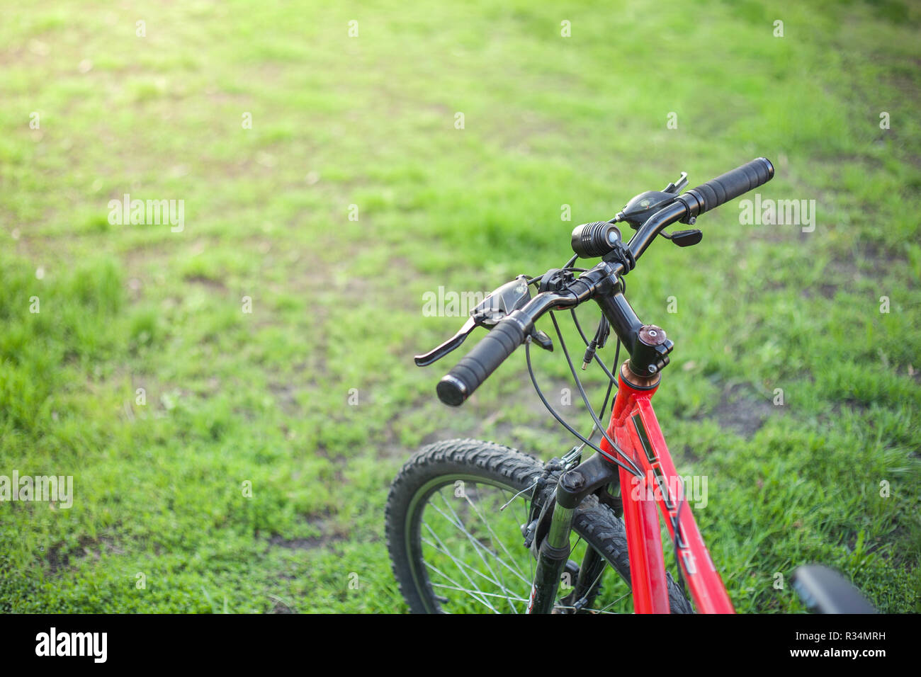 Mountain bike of red color with a black rudder on green grass Stock Photo -  Alamy