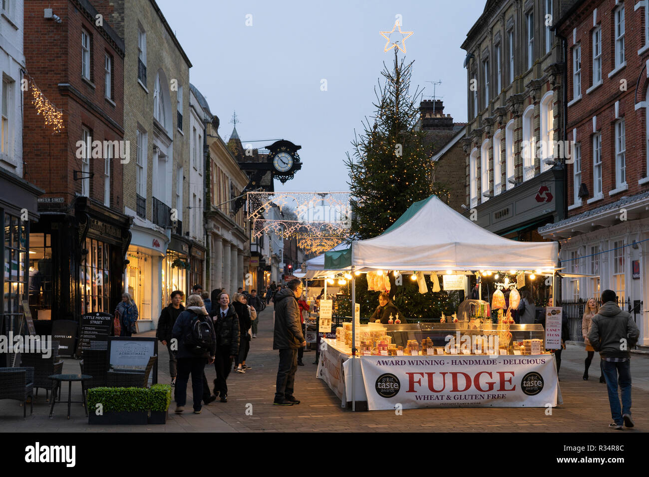 Shoppers looking at a fudge stall on Winchester High Street with a Christmas tree and lights in the background Stock Photo