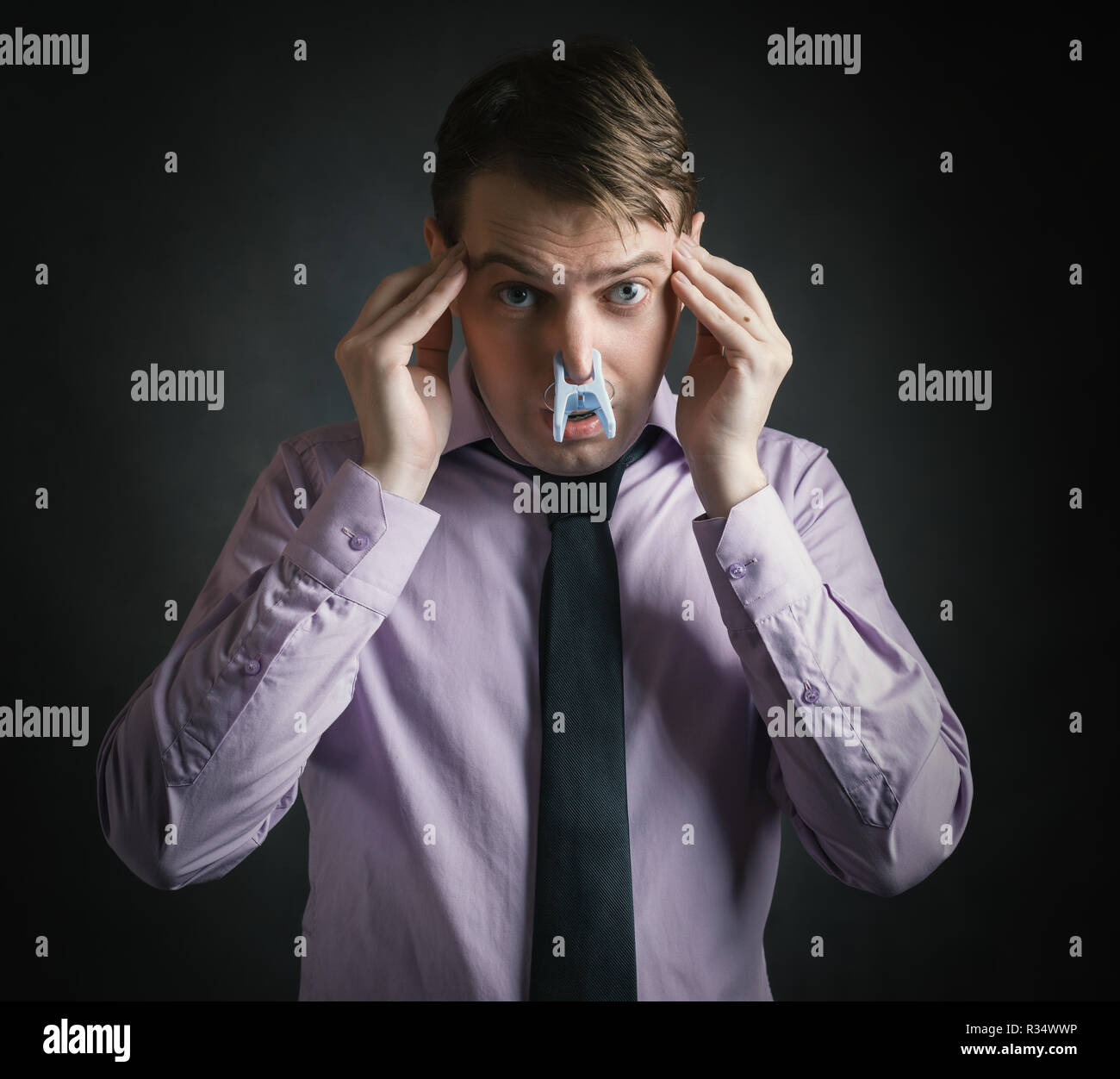 Portrait of young businessman man with clothespin on his nose bad