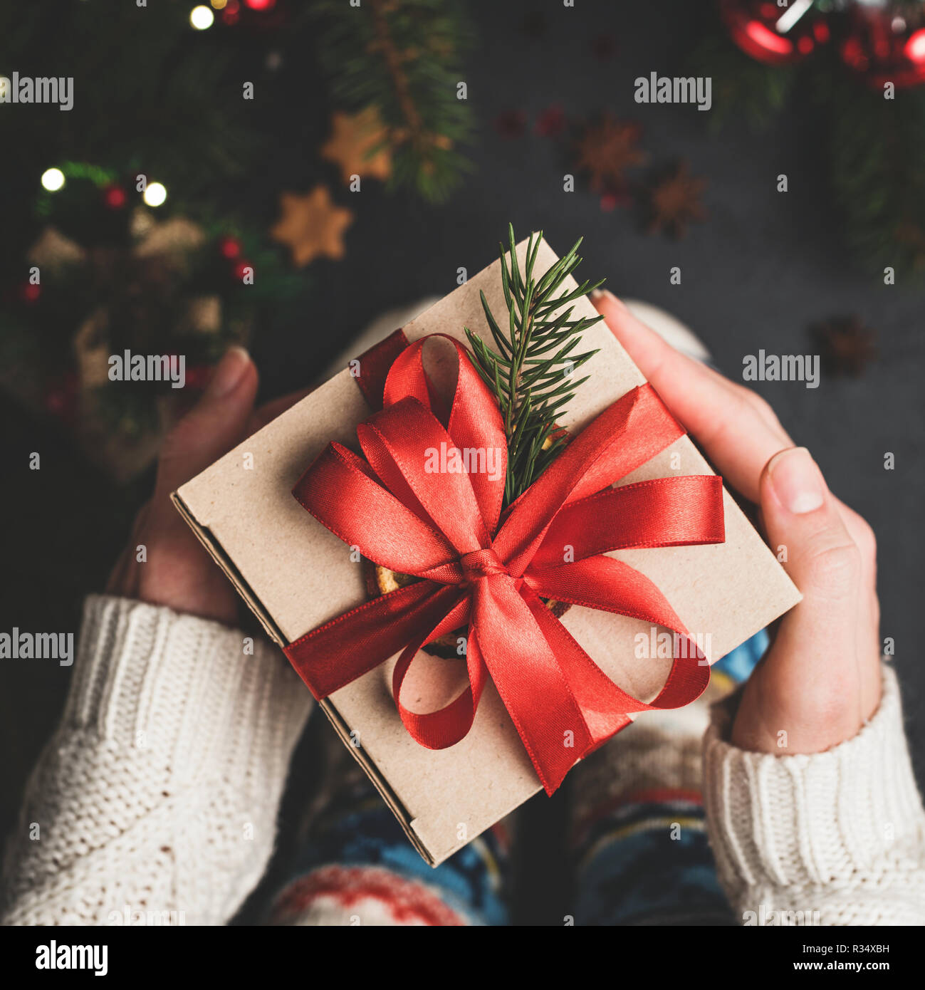 Christmas Gift Box With Red Lace In Hands. Craft Paper Gift Box Package. Hands Holding Christmas or New Year Present Stock Photo