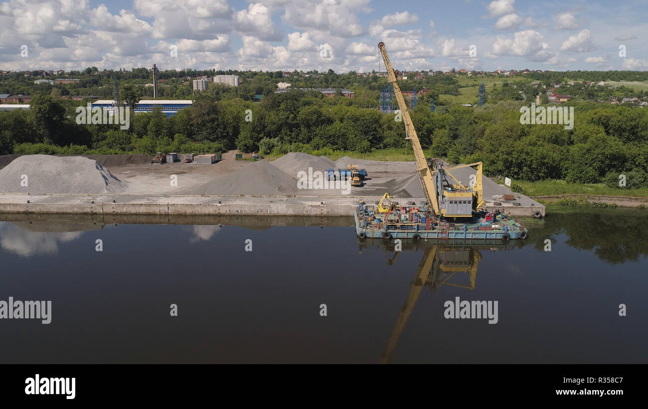 Aerial view large crane an excavator mounted on barge. Excavator on river for unloading and loading sand and rubble. Stock Photo