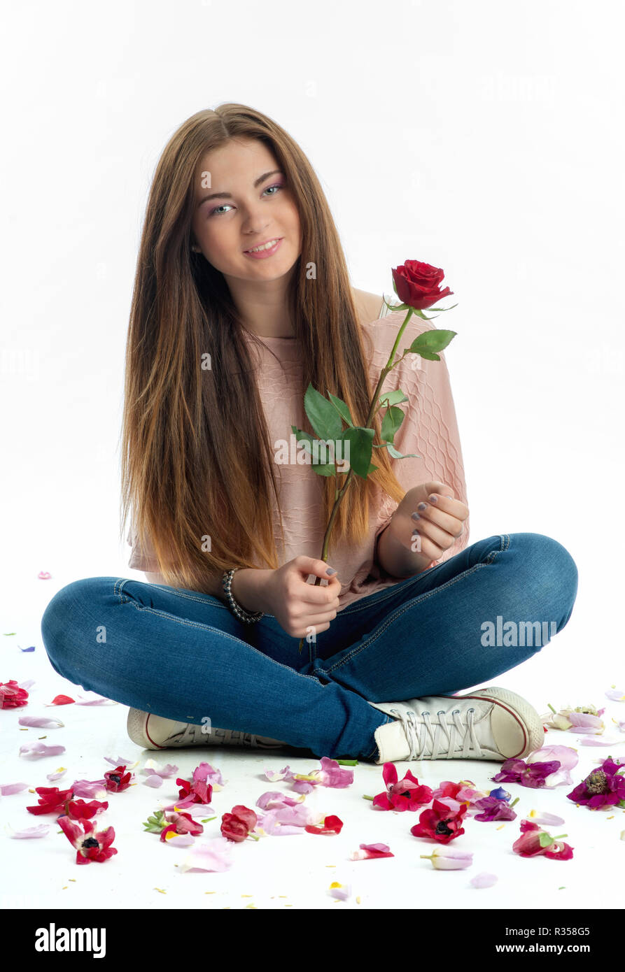 girl sits amid rose petals Stock Photo