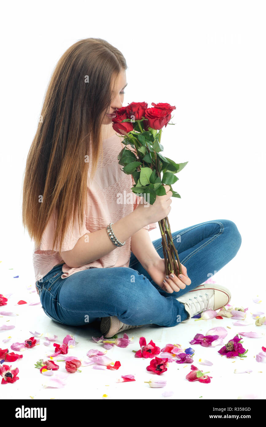 girl sits amid rose petals Stock Photo