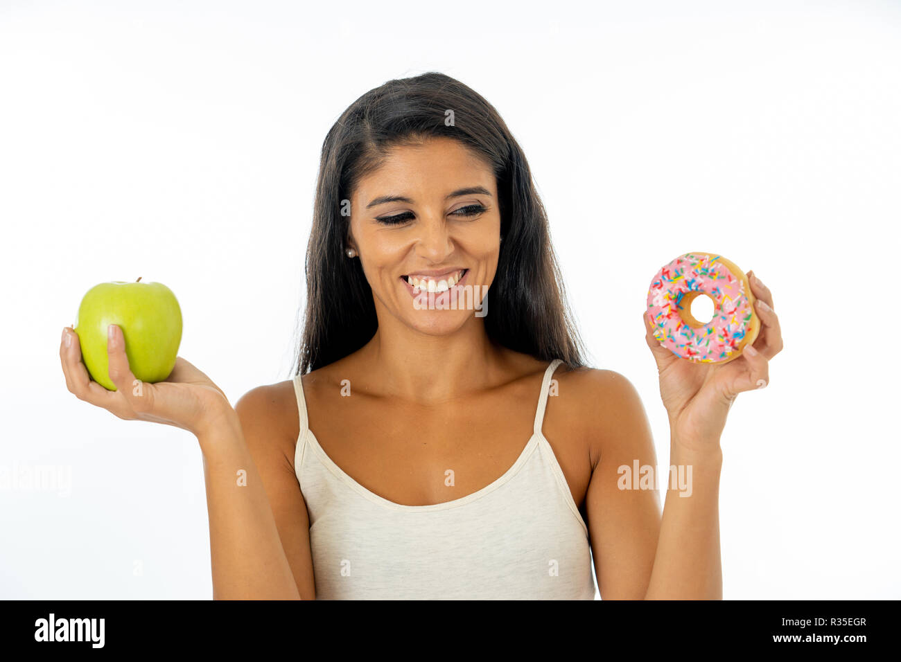 Beautiful happy young woman holding apple and doughnut in healthy unhealthy food, detox eating, calories and diet concept.. Stock Photo