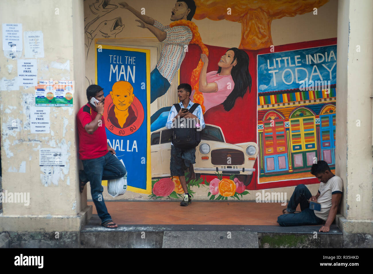 15.04.2018, Singapore, Republic of Singapore, Asia - Three men are waiting in front of a colourful wall mural in Little India. Stock Photo