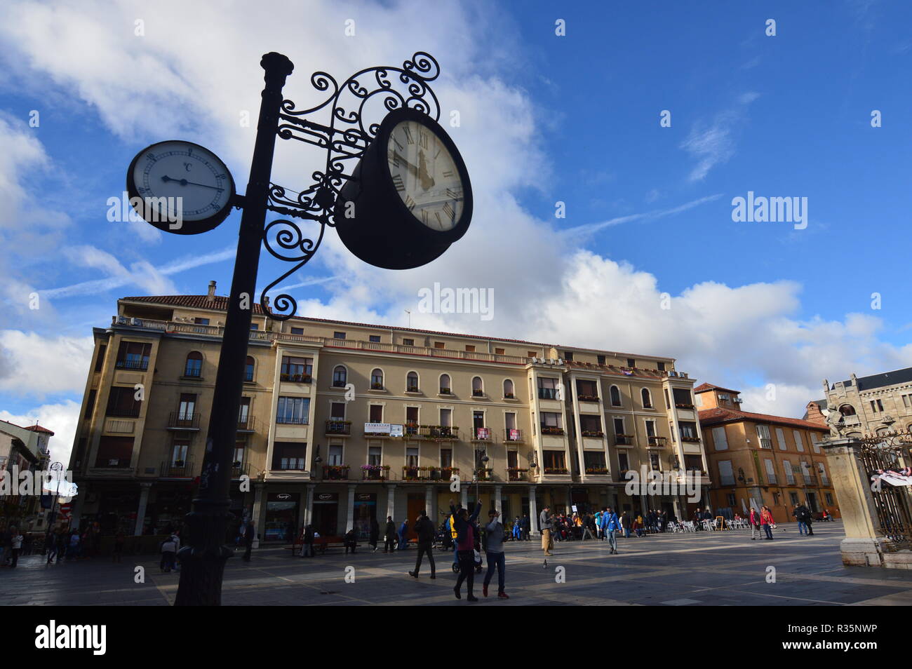Beautiful Clock And Analog Thermometer With Beautiful Buildings Behind The Cathedral Square In Leon. Architecture, Travel, History, Street Photography Stock Photo