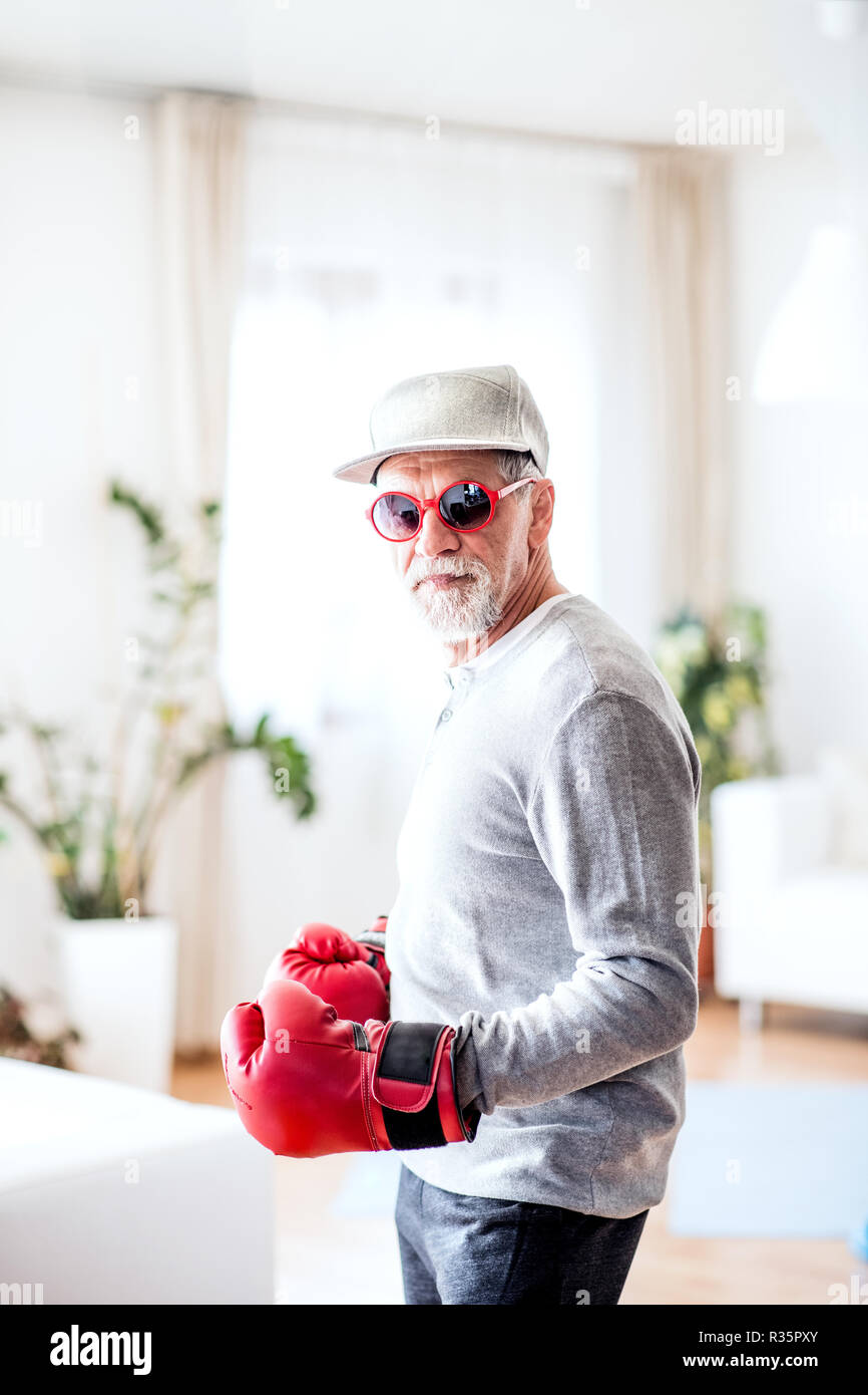 A senior man with boxing gloves having fun at home. Stock Photo