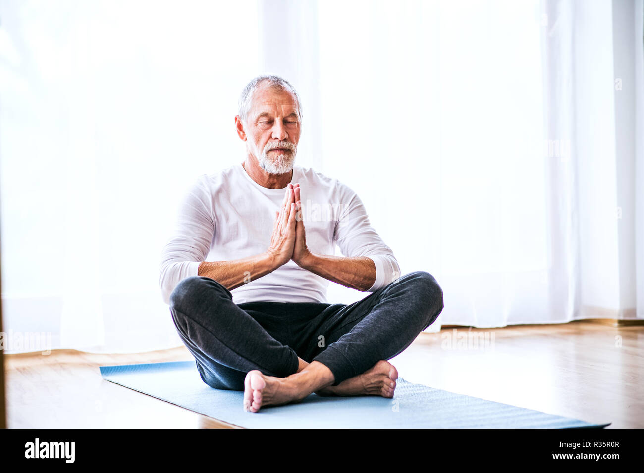 A contented senior man meditating at home. Stock Photo