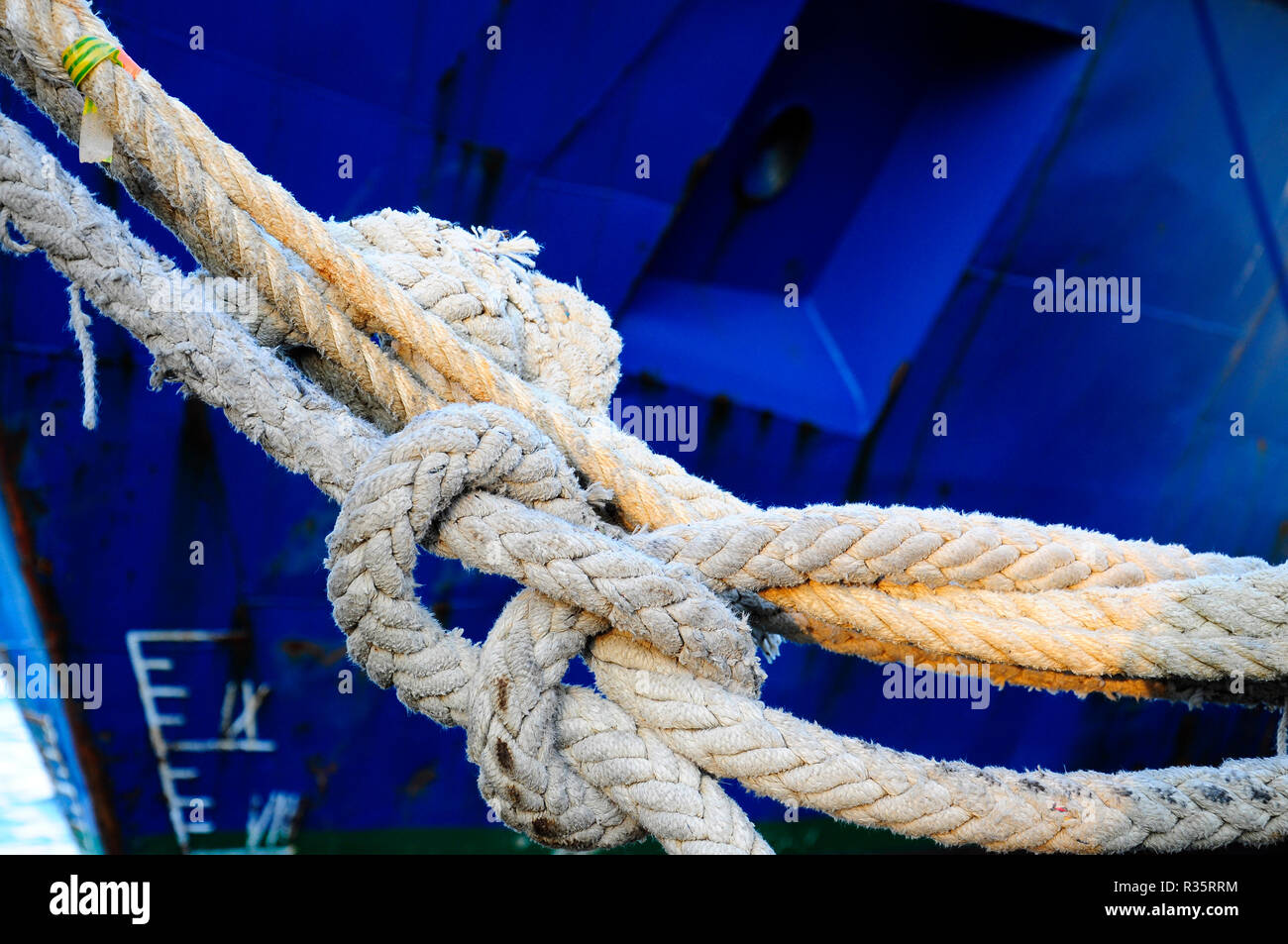 The mooring rope of a blue ship tied to the port Stock Photo