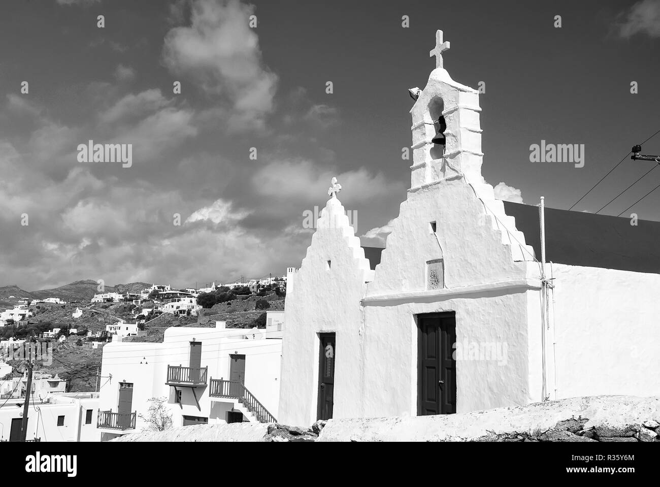 Church with bell tower Church building architecture on blue sky. Houses on mountain landscape. Summer vacation on mediterranean island. Religion and cult concept. Stock Photo