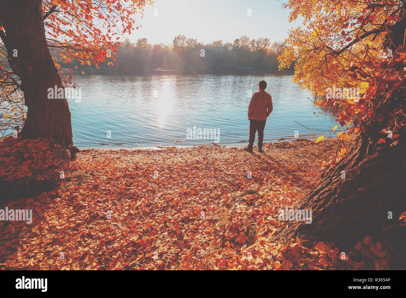 A Man Standing On The River Bank In Autumn And Looking At Water Stock Photo Alamy