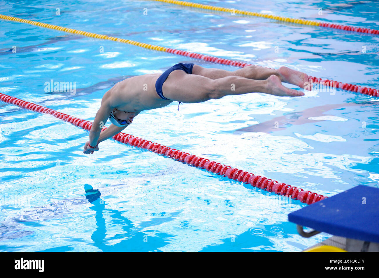 Male swimmer in bathing suit jumping into water of a swimming pool. Kiev, Ukraine. October 25, 2018 Stock Photo