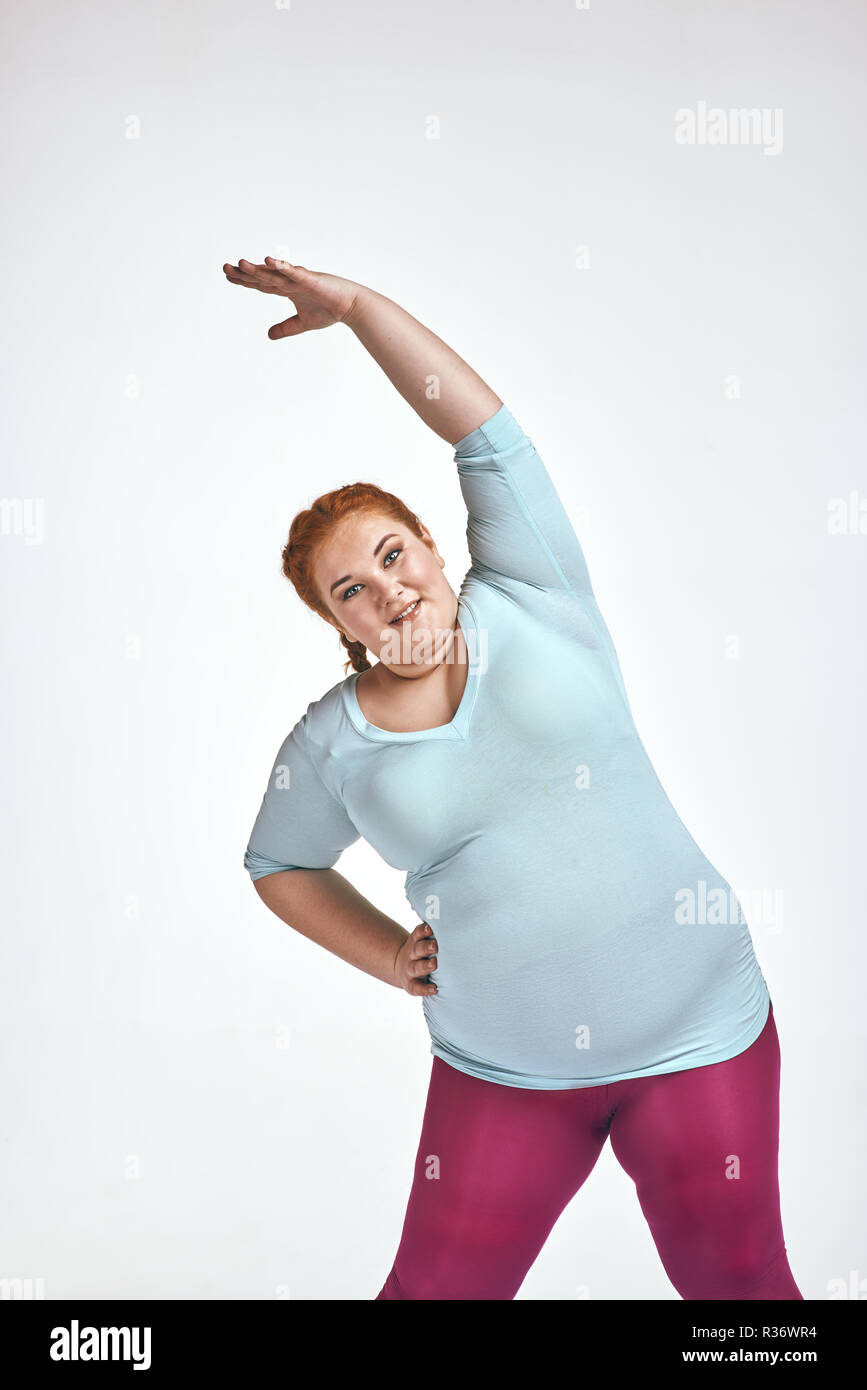 Amusing, red haired, chubby woman is doing exersizes Stock Photo