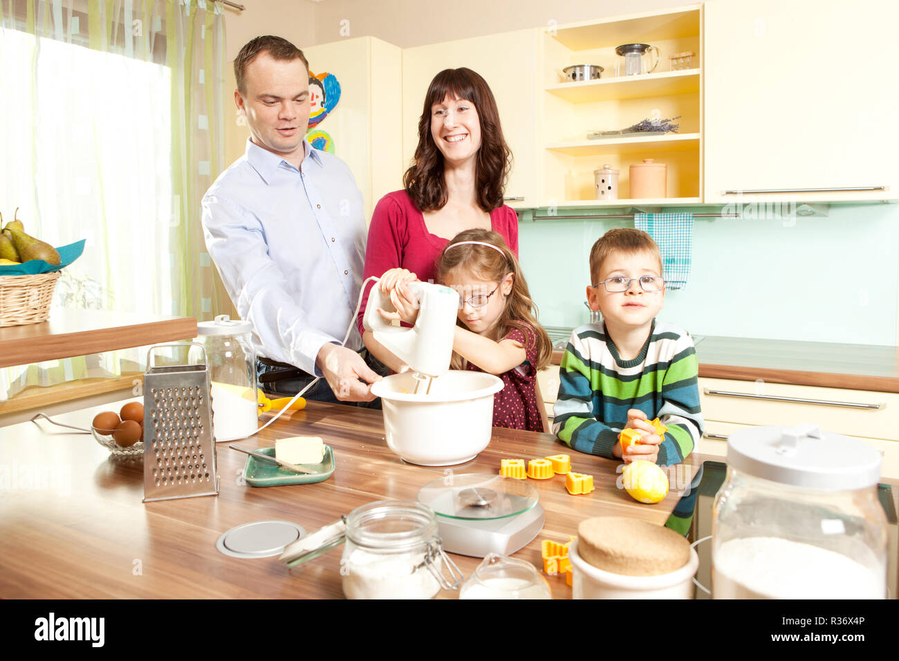 young parents bake in the kitchen with their children Stock Photo