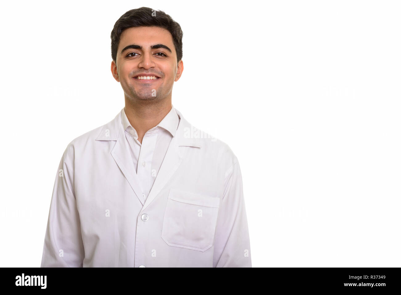 Young happy Persian man doctor smiling against white background Stock Photo
