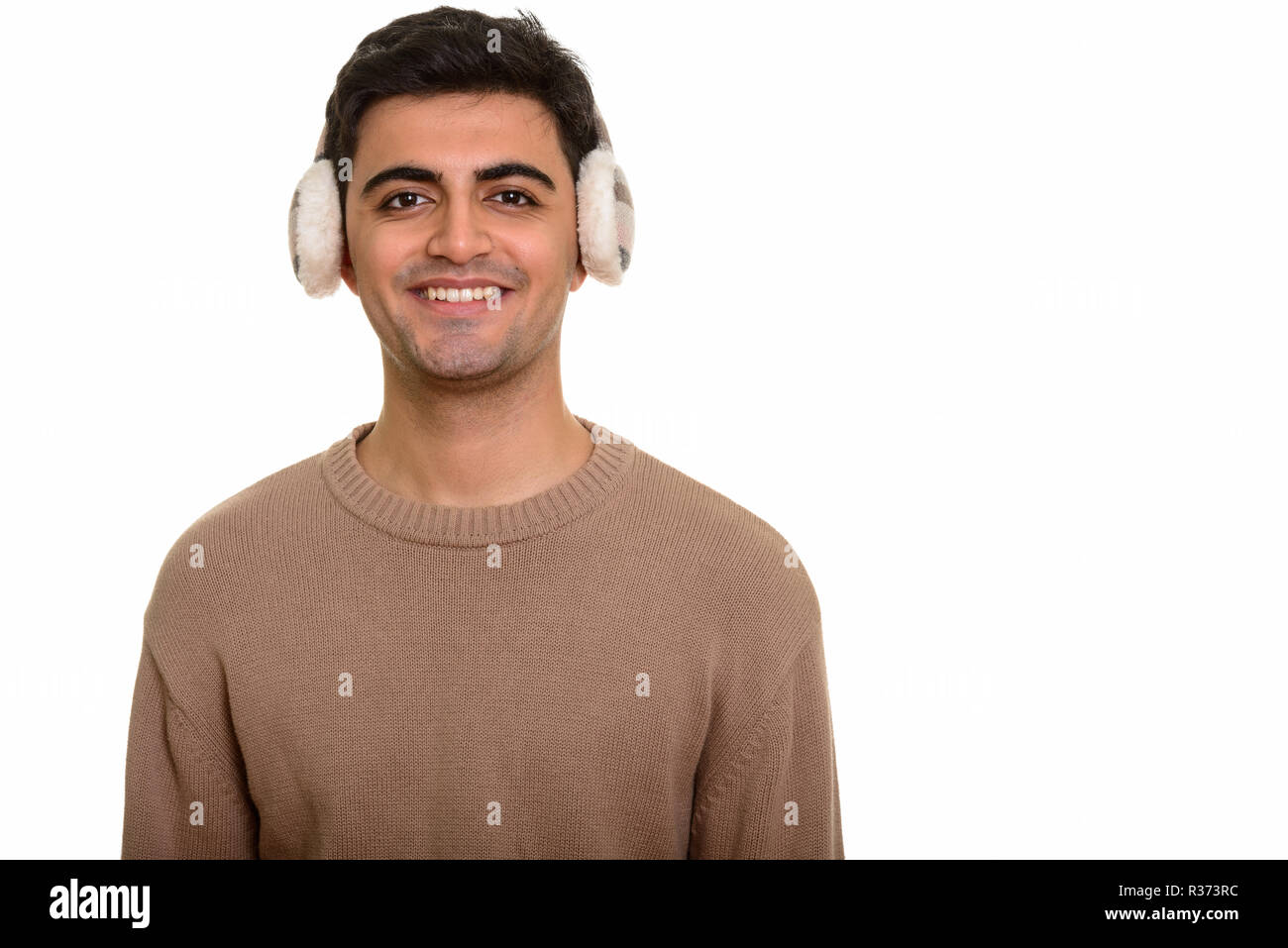 Young happy Persian man wearing winter earmuffs Stock Photo